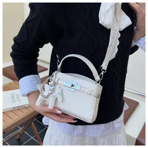 Close-up of a white crocodile-embossed handbag with lace shoulder strap and horse charm