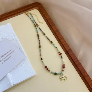 Detail of natural stone beaded necklace with a golden elephant pendant on a tray