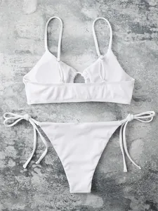 Macro detail of white ribbed bikini set with adjustable side tie strings on grey background