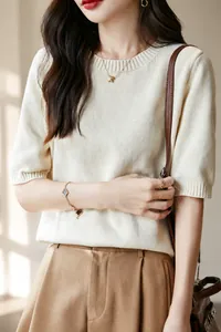 Dettaglio della trama in maglia di cotone beige e dell'elegante scollo rotondo sul capo