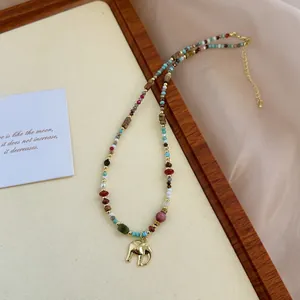 Macro detail of colorful natural stone beaded necklace with gold elephant charm