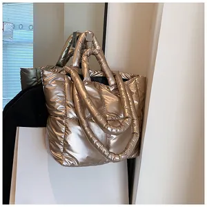 Detailed view of a metallic champagne gold puffer tote bag with soft quilted texture.