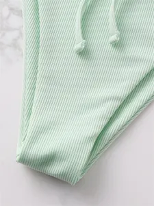 Macro detail of mint green ribbed fabric on a sexy drawstring bikini bottom swimwear