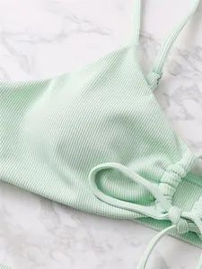 Detailed view of mint green ribbed bikini top featuring adjustable drawstring tie design