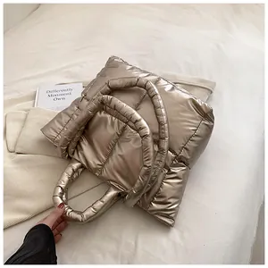 Champagne metallic quilted puffer tote bag displayed on neutral textured fabric