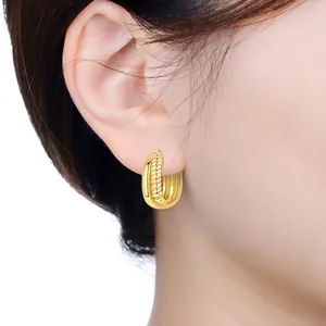 Detailed view of elegant 18K gold plated ribbed hoop earring worn on model's ear
