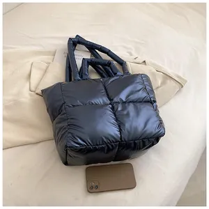 Large navy blue quilted puffer tote bag shown with a smartphone for size reference.