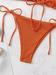 Close-up of orange ribbed bikini bottom with adjustable side drawstring ties