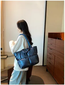 Deep blue metallic puffer tote bag shown on a model in a stylish indoor setting