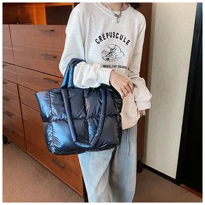 Close-up view of a shiny dark blue quilted puffy tote bag styled with a casual outfit.