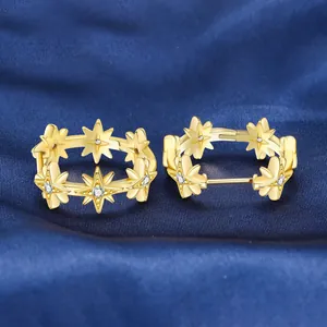 Detail of 18K gold plated starburst hoop earrings with crystal accents on blue silk.