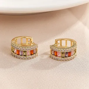 Macro view of gold hoop earrings featuring vibrant multi-colored rectangular crystals