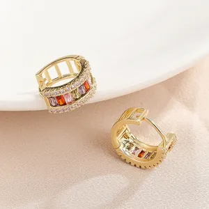 Detail showing multi-colored baguette zirconia on gold-plated huggie hoop earrings