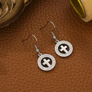 Detailed macro view of silver stainless steel cross earrings with sparkling crystals