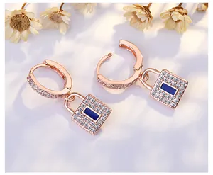 Macro view of rose gold lock earrings with pavé zircons and blue center stone