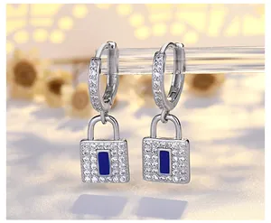 Macro view of silver padlock hoop earrings with iced-out crystals and blue inlay.