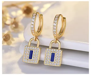 Close-up of gold hoop earrings featuring crystal-paved lock pendants with blue center.