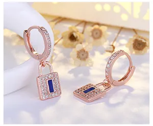 Detail view of rose gold padlock earrings with sparkling crystals and blue stone accents