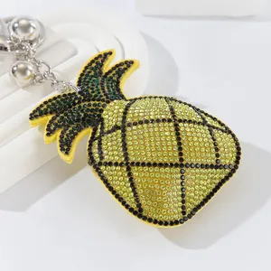 Close-up of cute sparkling yellow rhinestone pineapple keychain with silver bells