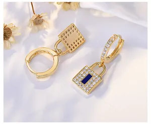Close-up view of gold-plated padlock hoop earrings encrusted with crystals and a blue stone