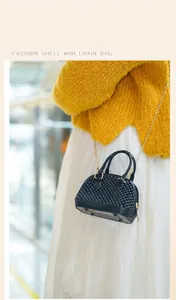 Close-up of a black studded PVC mini shell bag worn as a crossbody by a model.