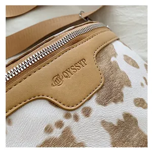 Gros plan détaillé d'un sac bandoulière motif vache avec fermeture éclair et cuir