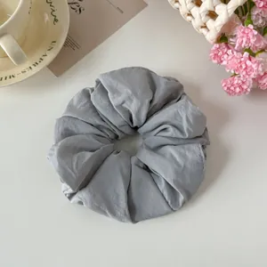 Macro detail of a grey oversized fabric scrunchie showing the soft pleated fabric texture.