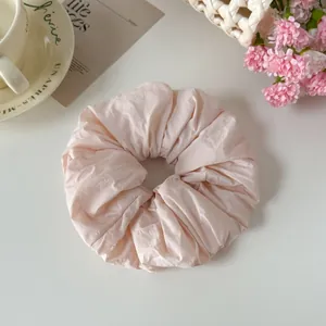 Soft pink fabric scrunchie hair tie with elegant crinkle texture for women's hair