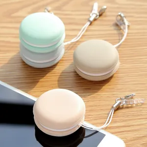 Cute macaron-shaped phone screen cleaner pendants in pastel colors on wooden surface