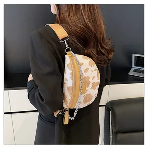 Détail d'un sac de poitrine à motif vache avec une large sangle et chaîne argentée