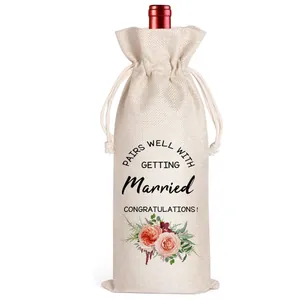 Nahaufnahme eines Jute-Weinbeutels mit Hochzeitsaufdruck und floralen Details.