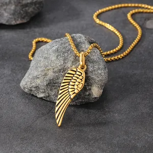 Detail view of a gold-plated stainless steel angel wing pendant on a natural stone