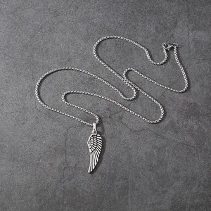 Detailed view of silver stainless steel angel wing pendant necklace on stone background