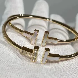 Detalle de brazaletes clásicos de doble T con nácar y detalles de piedras pavé