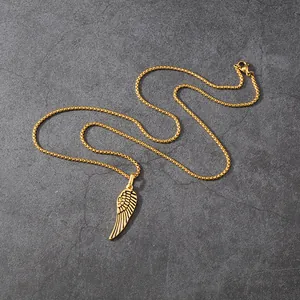 Detailed shot of a gold-plated stainless steel feather wing pendant on a stone background