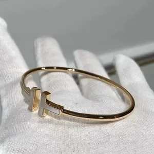 Primer plano detallado del inserto de nácar en un brazalete de oro rosa con doble T