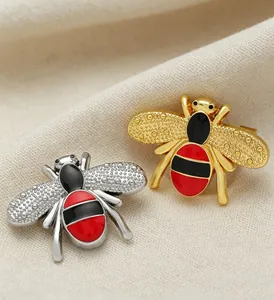 Close-up of elegant gold and silver bee brooches with red and black enamel detail