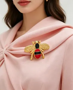 Detailed view of a gold-toned bee brooch with red and black enamel on a pink dress