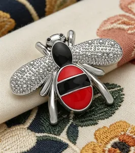 Detailed close-up showing the textured wings and red-black striped body of the bee brooch.