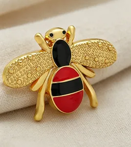 Macro view of a gold-toned bee brooch with red and black enamel stripes