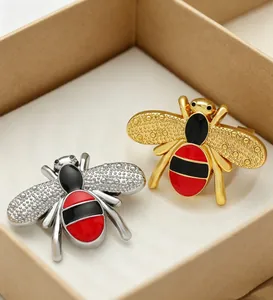 Detailed view of luxury style gold and silver alloy bee brooches with red and black enamel