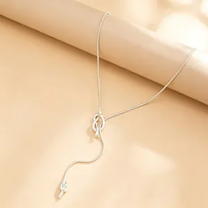 Detailed view of an elegant silver snake chain necklace featuring a chic knot and tassel.
