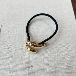 Detail shot of minimalist retro gold metal charm on a durable black elastic hair tie
