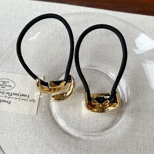 Close-up of elegant gold metal hair elastics with black rubber bands on a glass plate