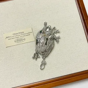 Elegant vintage silver anatomical heart brooch encrusted with clear crystals on a display.