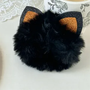 Detailed view of a fluffy black Halloween scrunchie featuring glittery orange cat ears