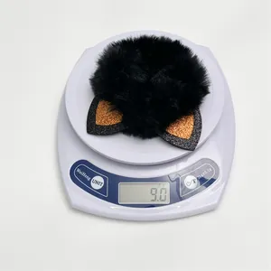 Close-up of black fluffy Halloween cat ear scrunchie on a digital scale weighing 9.0g