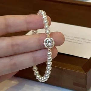 Detailed macro view of an elegant pearl bracelet with a central sparkling gemstone.