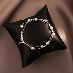 Close-up of elegant double-strand silver bracelet with white pearls on a display pillow.