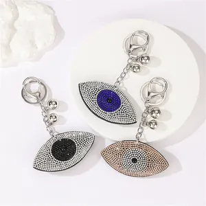 Detailed view of three rhinestone-encrusted evil eye keychains in different colors.